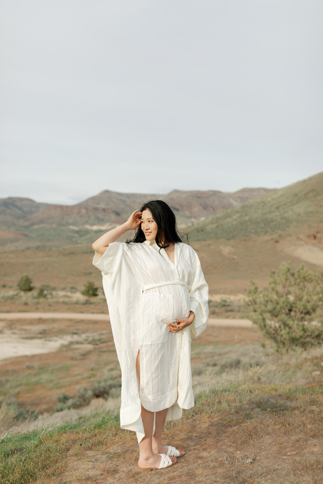 pregnant woman holding her belly and looking off to the left at the painted hills