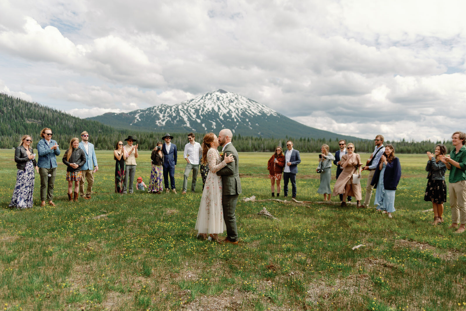 couple at sparks lake meadow with mountain in background, surrounded by family in a semicircle and watching them get married