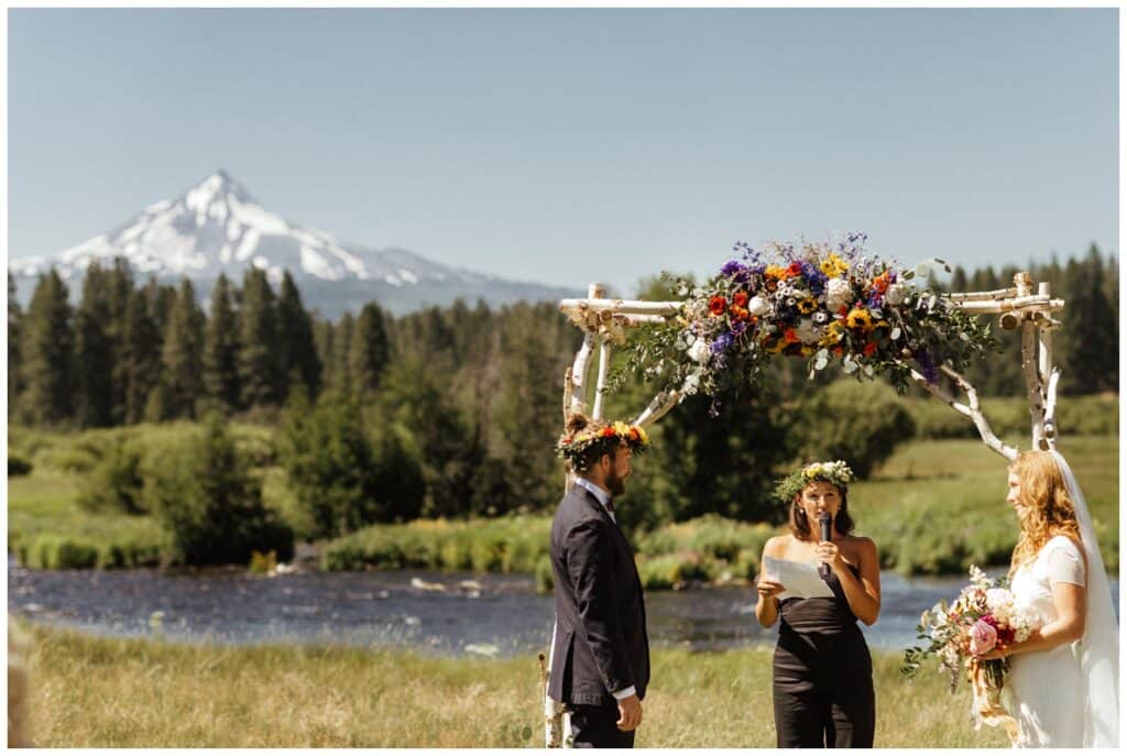 couple standing under alter during wedding ceremony with mountain in background.