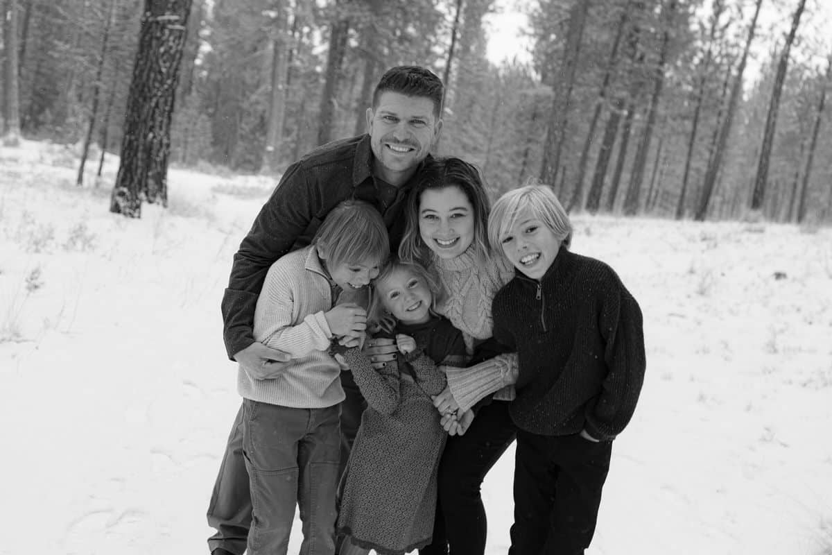 black and white photo of a family of 5 cuddling up together and smiling at the camera