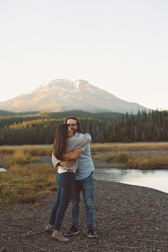 couple embracing and laughing with the cascade lakes highway in bend oregon behind them