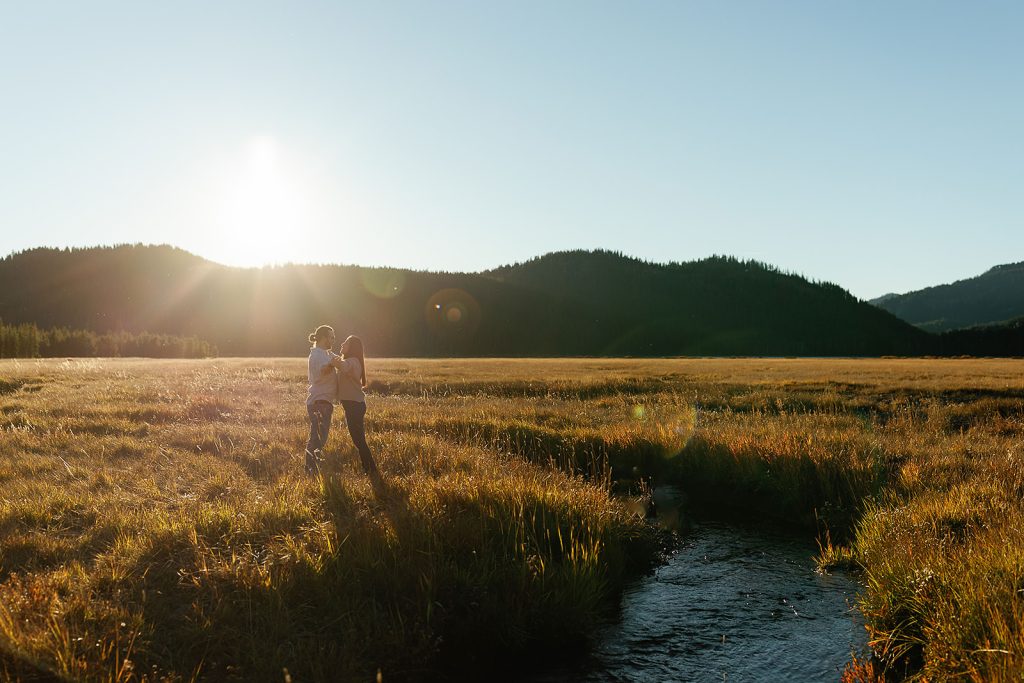 couple in field on cascade lakes highway facing each other and holding hands