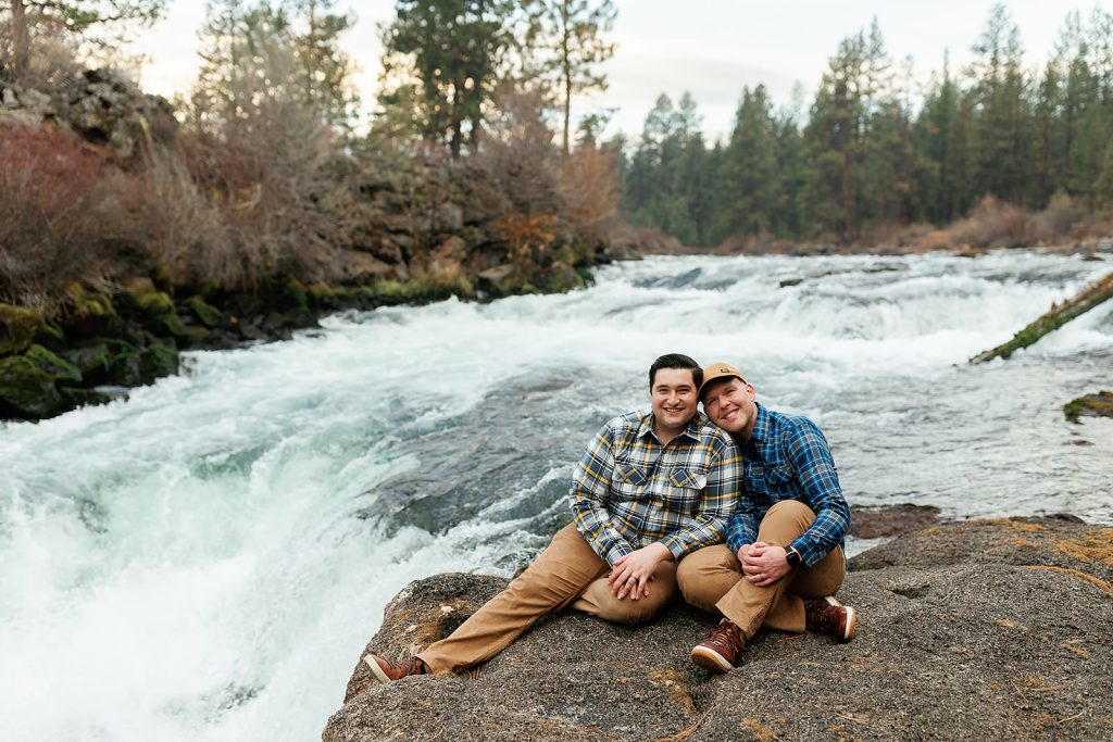 a couple sitting above dillon falls smiling at the camera and cuddling