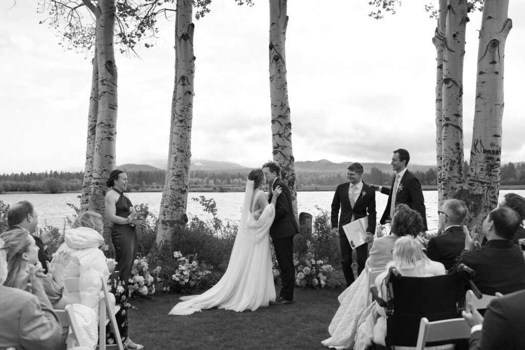 couple kissing during their wedding ceremony at black butte ranch between the ponderosa trees
