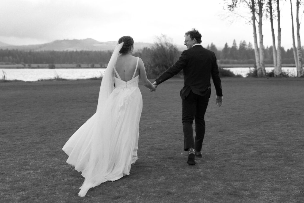 black and white image of a couple in wedding attire walking away from the camera