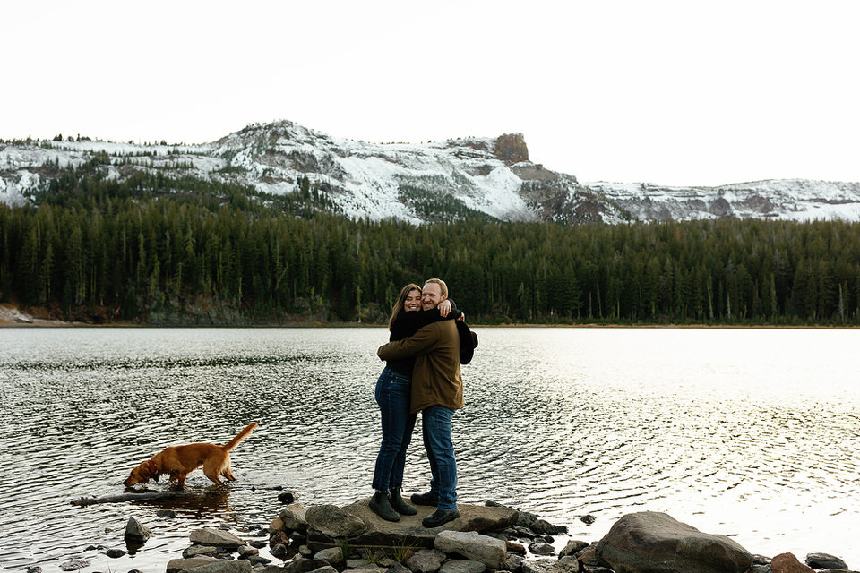 couple standing on a rock hugging with a mountain view in the background